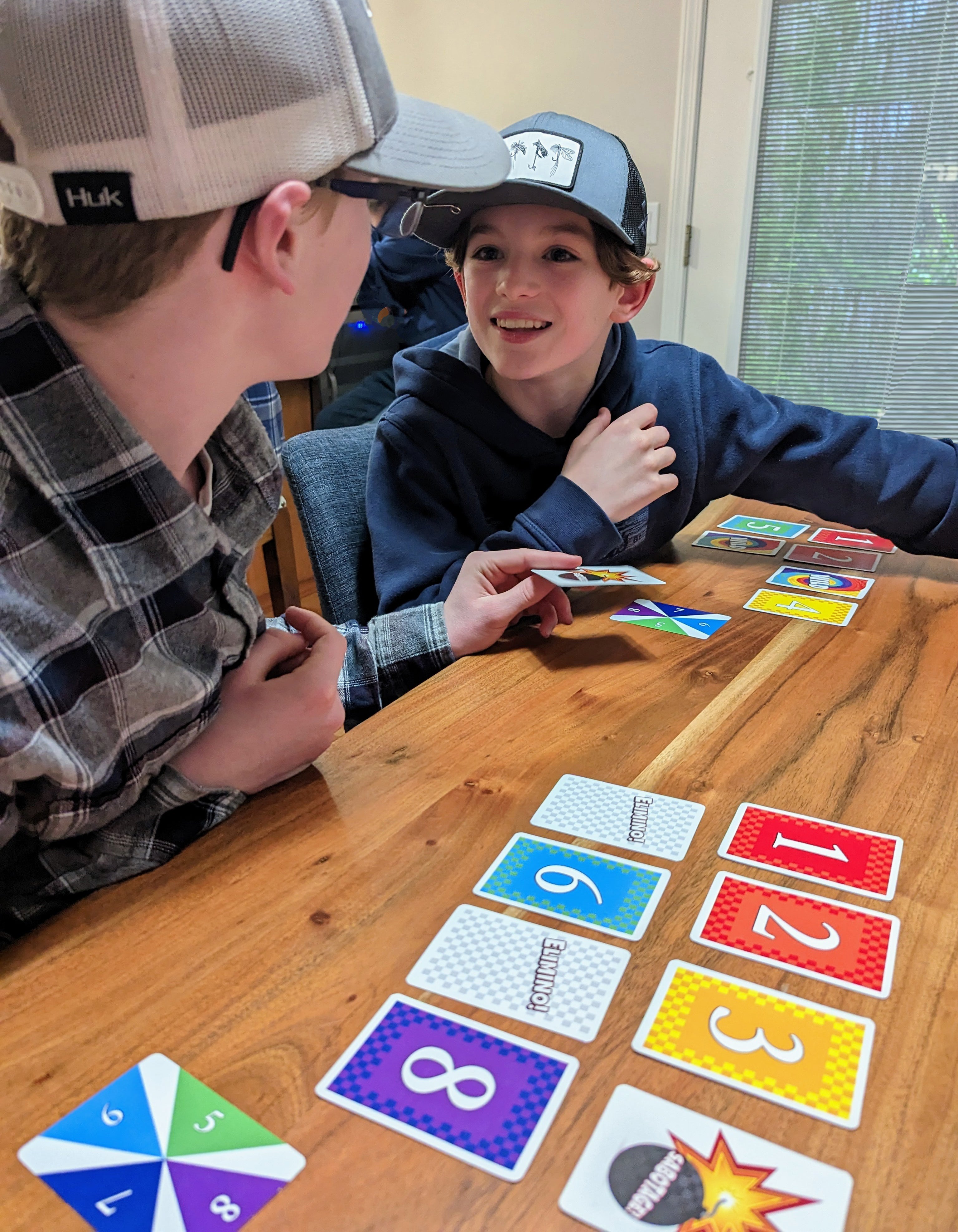 Boys playing Elimino with cards on a table